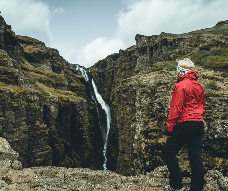 Picture of Jeannie on Top of a Rocky Mountain Looking at the Glymur Waterfall | Iceland with a View 