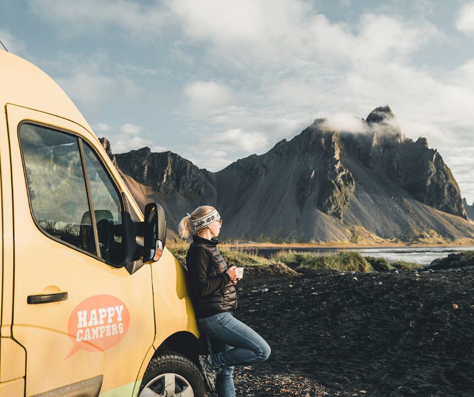 Picture of Jeannie from Iceland with a View Leaning on her Happy Campers Iceland Rental Campervan Admiring the Beautiful View While Drinking Coffee