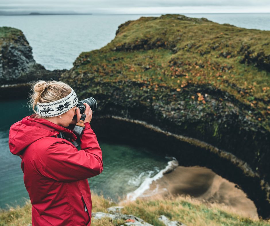 Picture of Jeannie Taking a Picture of the Snaefellsnes Arnarstapi Cliffs View With Her Camera, A must item Under Iceland Fall Packing List | Iceland with a View