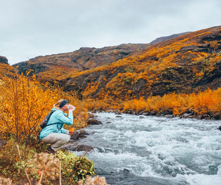 Picture of Jeannie Wearing Raincoat and Drinking Glacier water Straight from Earth | Iceland with a View