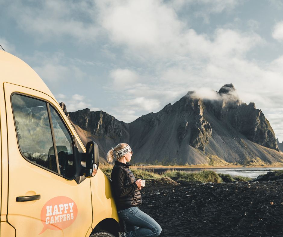 Picture of Jeannie Riley Drinking a Cup of Coffee While Leaning Against the Happy Camper van Admiring the View of Stokksnes | Iceland Apps | Iceland with a View