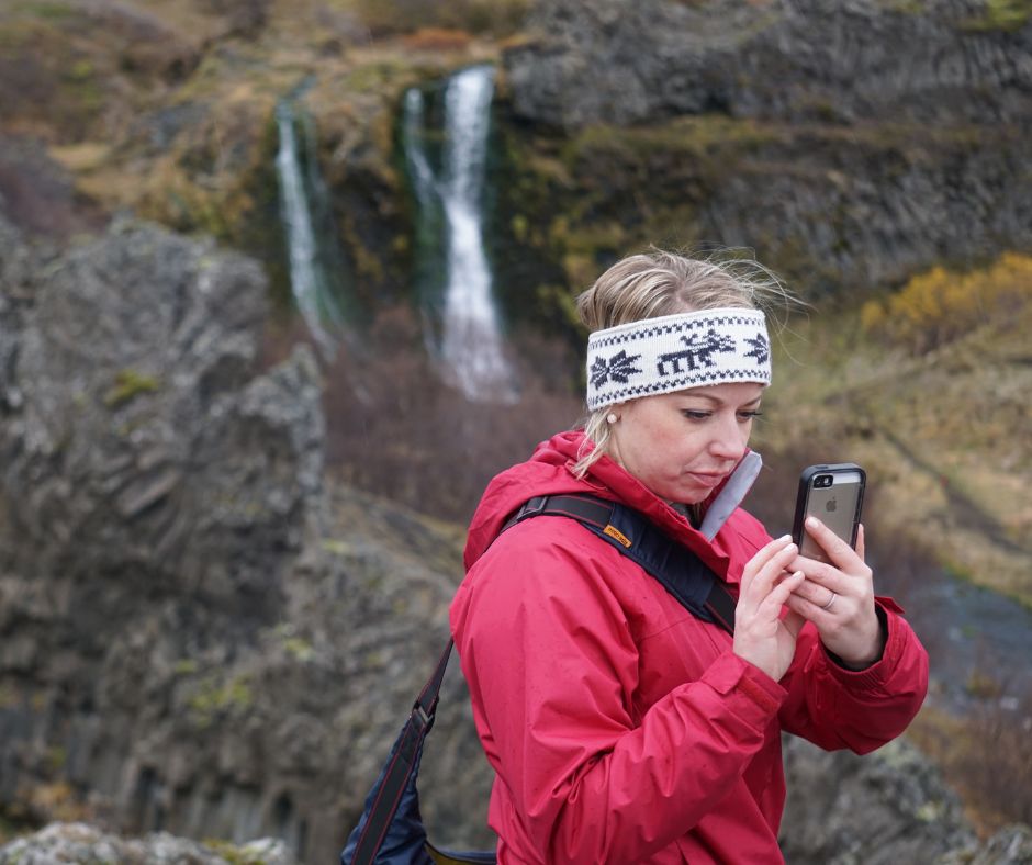 Candid Picture of Jeannie Wearing her Red Raincoat and Headband and Using Her Phone | WIFI in Iceland | Iceland with a View