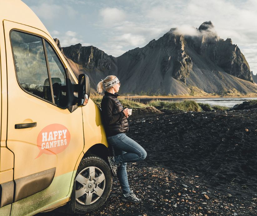 Picture of Jeannie Leaning Against the Happy Camper Van (One of the Many Ways You Can Transport in Iceland), Drinking Coffee, and Admiring the View of Stokksness | Iceland with a View 