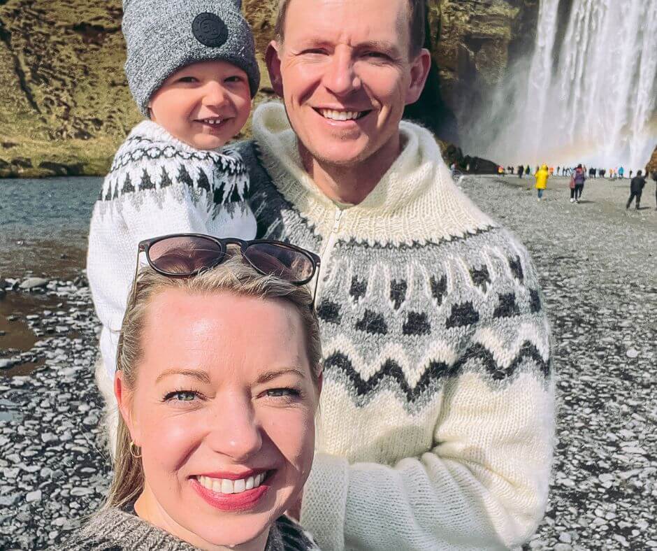 Jeannie with her kid and husband smiling on camera on Skógafoss waterfall | Iceland Family Holiday | Iceland with a View 