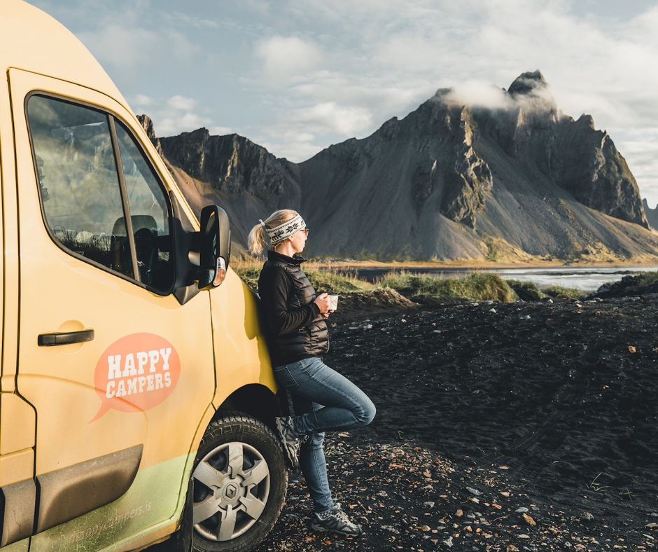 Picture of Jeannie Drinking a Cup of Coffee Laying on the Happy Camper Van While Admiring the Landscape View of Stokksnes in Iceland | Iceland with a View 