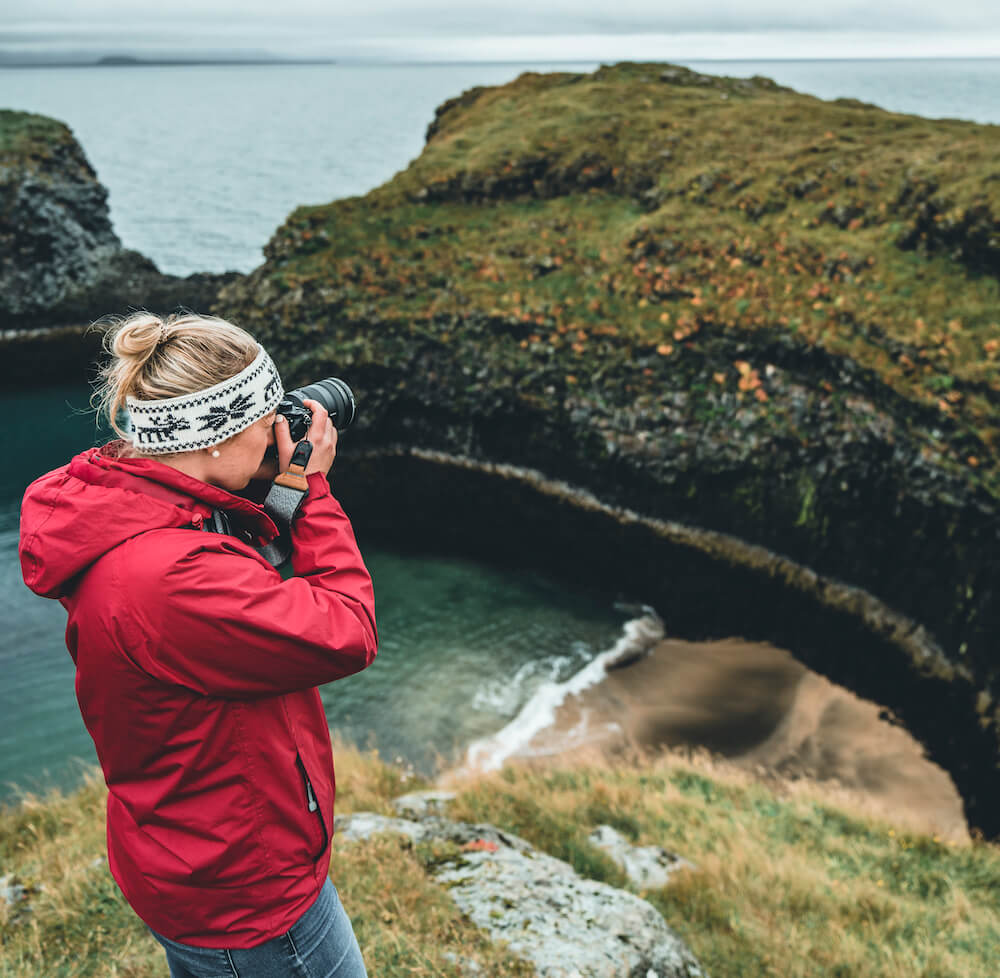 Picture of Jeannie wearing layers for the weather while taking a picture of Snaefellsnes with her camera | Iceland in October | Iceland with a View 