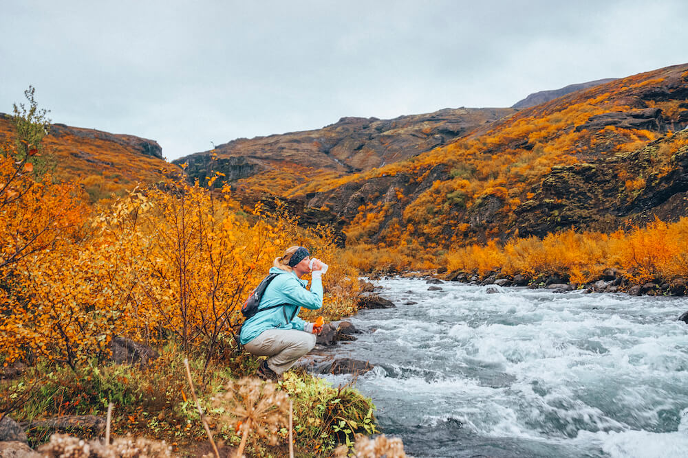 Picture of Jess Drinking from Pure Glacier Water at the Stream on Glymur Waterfall River | Glymur Waterfall | Iceland with a View