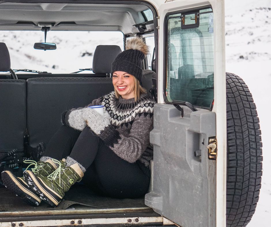 Picture of Jeannie Sitting at the Back of Her Car Drinking Coffee Wearing an Icelandic Lopapeysa and Layers for Winter | Icelandic Winter Packing List | Iceland with a View