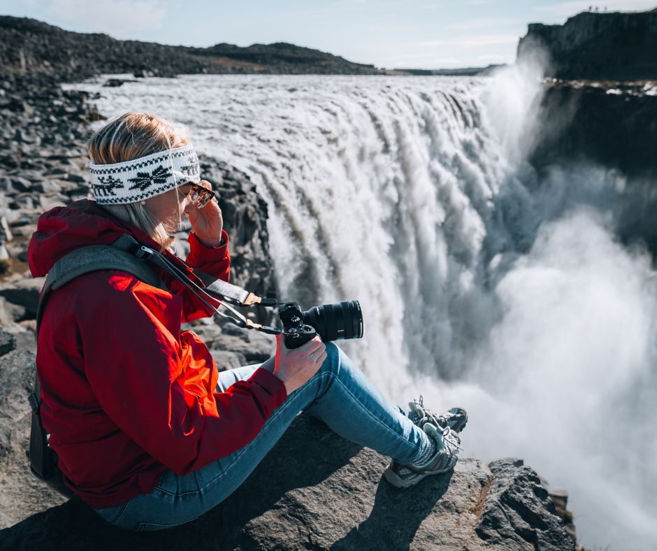 Picture of Jeannie Sitting on the Edge of Dettifoss While Setting Up Her Camera to Take Photos in Iceland